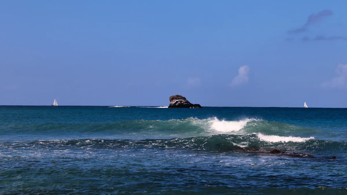 Voilier naviguant entre deux îles volcaniques des Caraïbes, vue complémentaire pour ferry Martinique Dominique